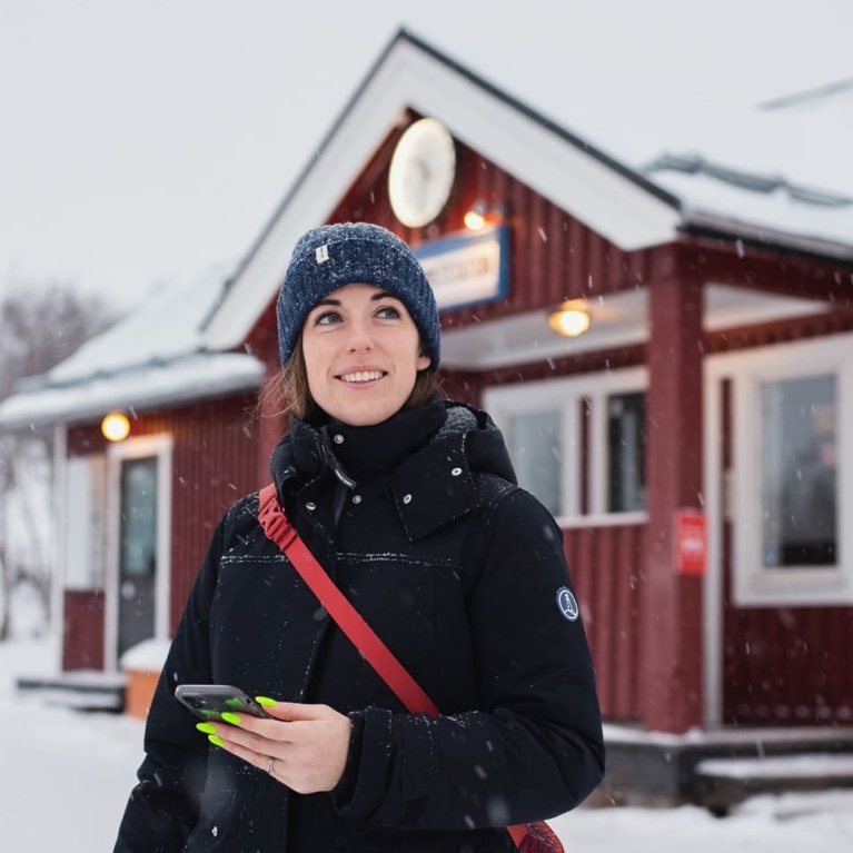 Rachel Schnalzer stands outside of a snow-covered train station